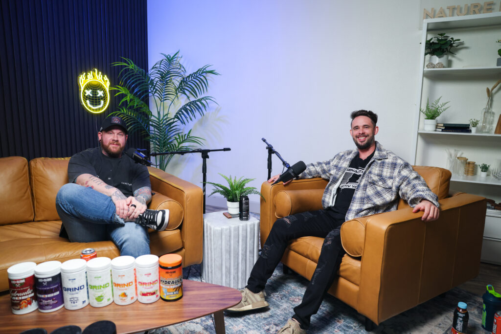 Two men recording a podcast in a modern studio surrounded by supplement products. Represents authentic supplement brand marketing and behind-the-scenes content.